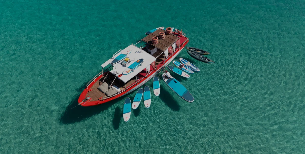 Dronebeeld van Salvador Ibiza in Cala Comte met turquoise water en schaduwen van paddleboards